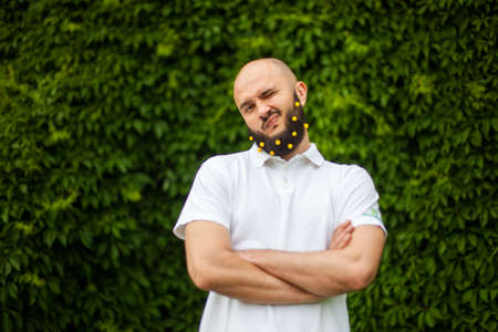 Portrait of funny man with decoration in his beard with green floral backgroundの写真素材