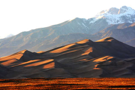 Sunset on Golden Great Sand Dunes with the background of snowcap on top of the mountainの写真素材
