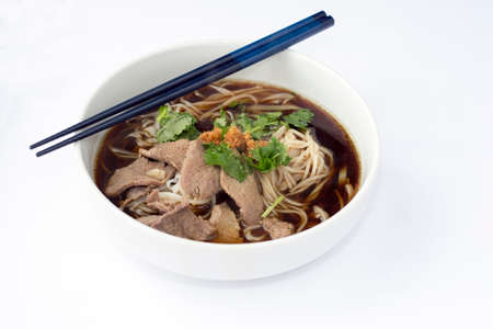 Close Up Thai Style Beef Rice Noodles Soup in Ceramic Bowl on White Fabric Background