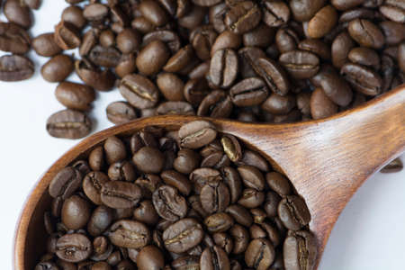 Medium roasted whole coffee bean in wooden spoon on coffee bean backgroundの写真素材