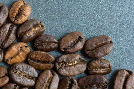 Close-up roasted whole coffee bean on gray baking sheet backgroundの写真素材