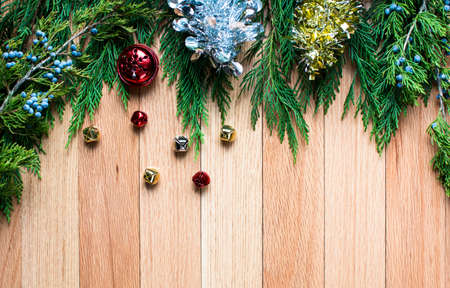 christmas jingle bells on hard wood floor background with green leaves top frame