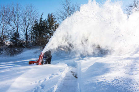 A man in black dress using a snow blower plowing snow after Jonas snow storm in the morningの写真素材