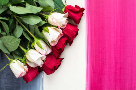 Mixed red and white roses lay flat on colorful stripes painted wood background, Top shot of red and white roses on colorful painted backgroundの写真素材