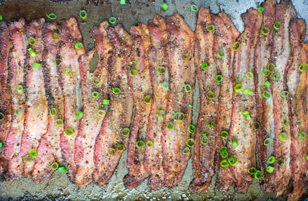 Oven baked peppercorn bacon garnish with chopped green onions in baking sheetの写真素材