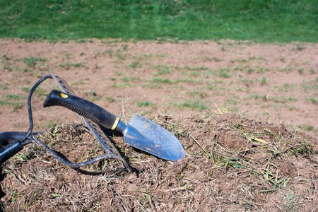Dirty gardening tools on pile of dirt and grassesの写真素材