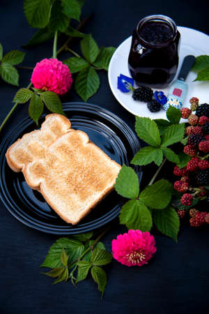 Two pieces of Toasted on Black Plate with Homemade Organic Blackberry Jam in a Glass Jar Decorated...