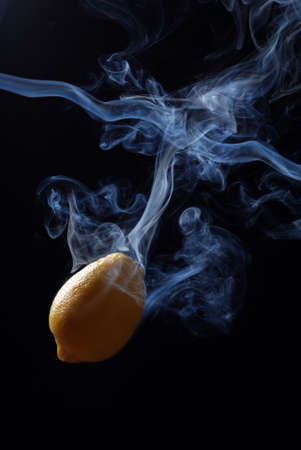 yellow lemon enveloped by smoke on a black background