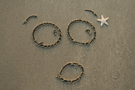 Handwrited face on the sand at the beachの写真素材