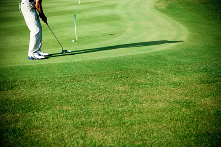 a golfer stepping up to his ball on the green grass