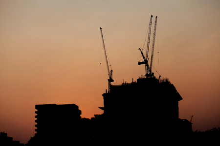 House under construction and tower cranes on the background of the setting sunの写真素材