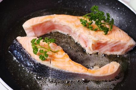 fresh slice of salmon in the frying panの写真素材