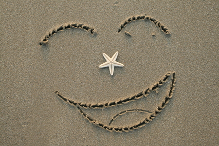 Handwrited face on the sand at the beachの写真素材
