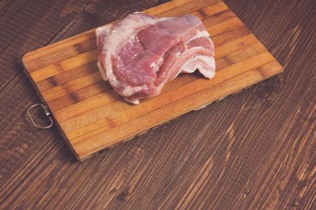 On a plank is a big piece of pork at the tableの写真素材
