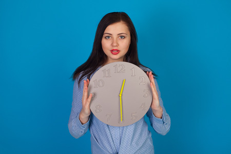 Woman is holding a grey clock clock in her handsの写真素材