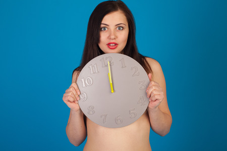 Naked woman is closing down with her grey clockの写真素材