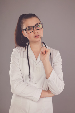 Thinking nurse ia standing against of grey backgroundの写真素材