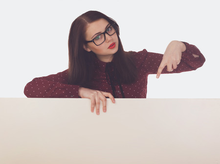 Woman with black glasses and red lips is holding a white canvas  in her hands against of white backgroundの写真素材