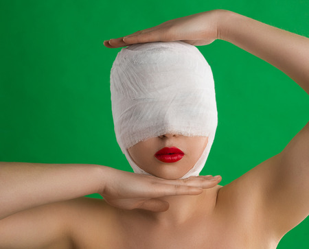 The woman with a bandage on her head and with full red lips is posing against the background of chromakey.の写真素材