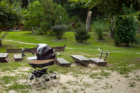 Brown baby carriage standing on the meadow in the green park on the background of treesの写真素材