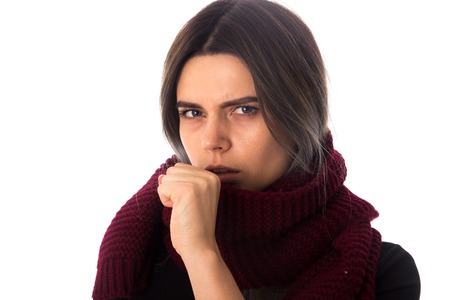 Sick young woman with dark hair in black shirt with long vinous scarf cuoghing on white background in studioの写真素材