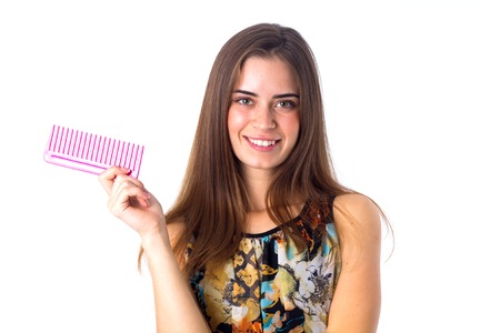 Young smiling woman in colored shirt with long brown hair holding pink hair brush on white background in studioの写真素材