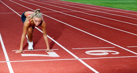 Beautiful sporty woman preparing to run at the start lineの写真素材