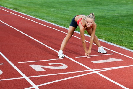 Woman in a sports suit doing training exercises before running