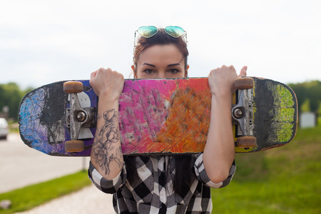 The woman is hidding her face with a skate on the background of park.の写真素材