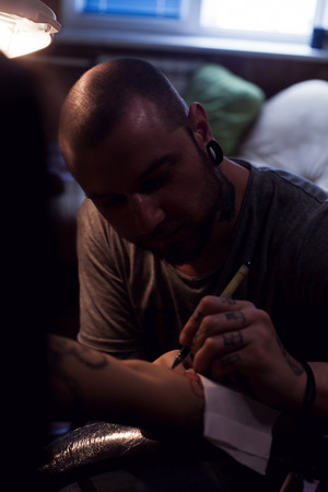 Tattooer is drawing scetch on the woman's hand using spesial marker の写真素材