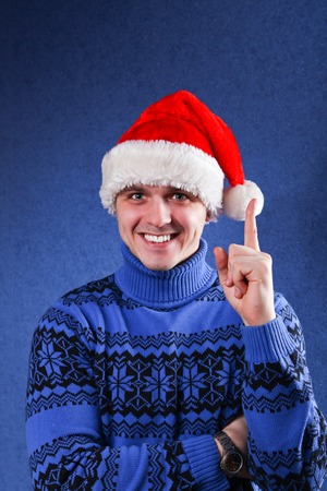 Man in blue sweater and red chrismas hat at blue background
