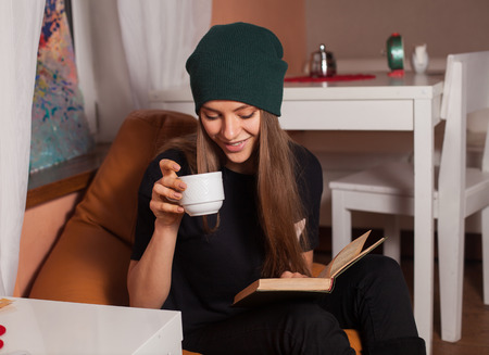 Woman reading book and drinking tea in cafe