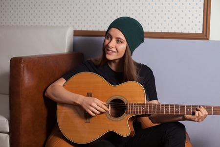 Woman hipster playing on guitar and singing
