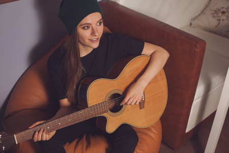 Woman hipster playing on guitar and enjoying musicの写真素材