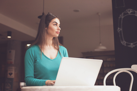 Woman-freelancer with glasses is looking through the window at the tableの写真素材