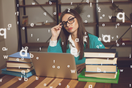 Woman is tired. She is working with lots of books and laptopの写真素材