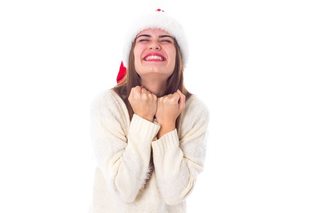 Young attractive woman in white sweater with red christmas hat showing happiness on white background in studioの写真素材