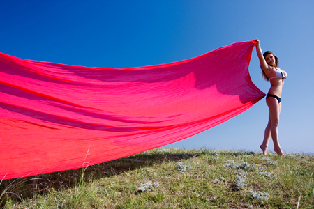 young beautiful woman standing with red materialの写真素材