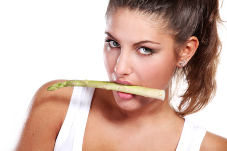 woman with fresh rgeen asparagus in her mouthの写真素材