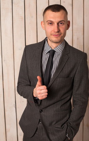 Business man in suit standing behind wooden wallの写真素材