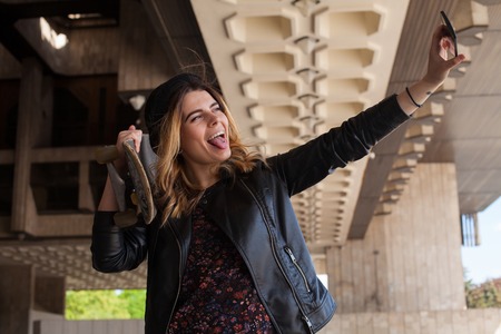 Young girl making selfie with the skateboard with her mouth openの写真素材