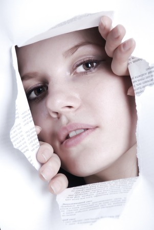 Beauty woman looking through hole in white paperの写真素材