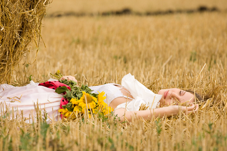 Woman in dress with flowers in the fieldの写真素材