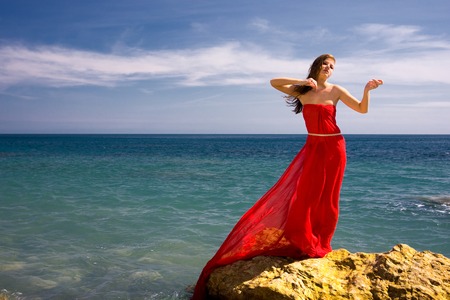 Beautiful woman in red dress at the sea beach の写真素材