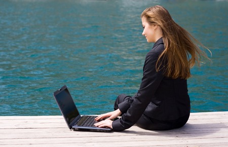 woman in black business suit sitting with laptop near the seaの写真素材