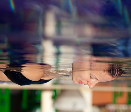 Beautiful young woman in a swimsuit lying on the water in the pool