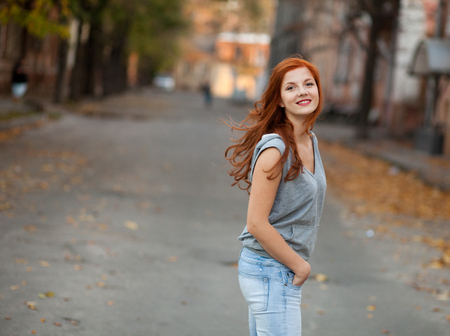 Woman with red hair walking by the streetの写真素材