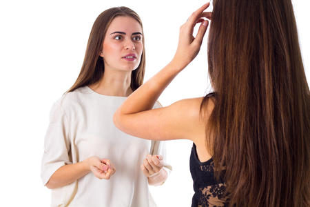 Young charming woman in white shirt talking to another one on white background in studioの写真素材
