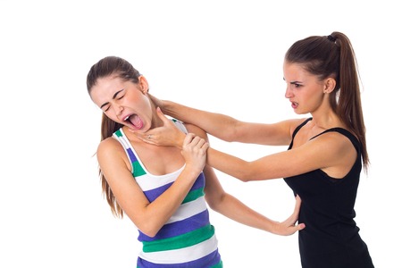 One young evil woman in black shirt keeping another woman's throat on white background in studioの写真素材
