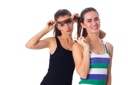 One young attractive woman in black shirt holding another woman's hair and showing OKAY on white background in studioの写真素材